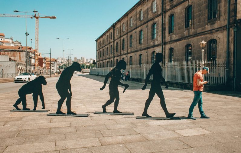 Silhouette of human evolution alongside a person walking in a modern urban setting.