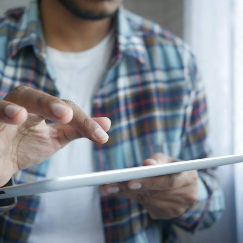 A person in a checkered shirt interacts with a tablet device.